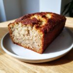 A close-up of a slice of moist cottage cheese banana bread with a deeply browned, sugary crust.