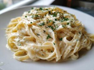 Close-up of fettuccine pasta coated in rich, creamy olive garden alfredo sauce, garnished with parsley.