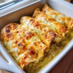 Close-up of three baked green chile chicken enchiladas covered in melted, bubbly, browned cheese.