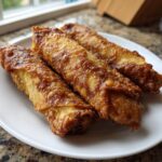 Three perfectly golden brown and crispy egg roll appetizers resting on a white plate.