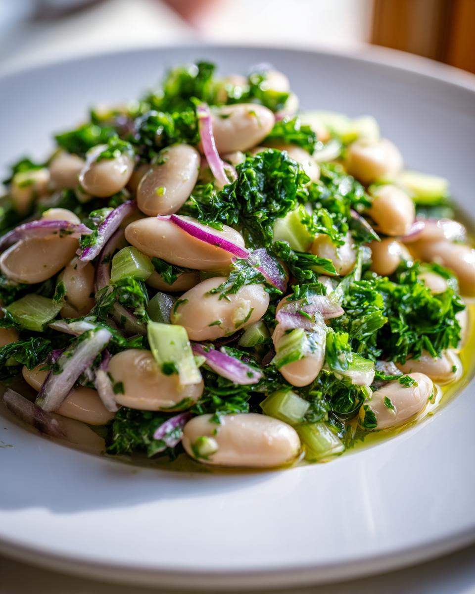 A close-up of a vibrant white bean salad mixed with chopped greens and red onion slices, glistening with dressing.