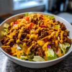 A close-up of a Big Mac Salad featuring lettuce, seasoned ground beef, tomatoes, and a generous drizzle of special sauce.