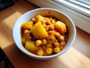 A close-up view of a white bowl filled with vibrant chickpea and potato curry recipe.