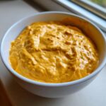 A close-up of thick, creamy, orange beer cheese dip served in a white bowl, perfect for game day.