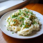 A mound of creamy low calorie mashed potatoes topped generously with fresh chopped chives and black pepper.