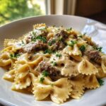 Close-up of creamy parmesan garlic beef bowtie pasta tossed in a rich sauce and garnished with fresh parsley.