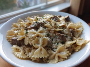 A close-up of creamy parmesan garlic beef bowtie pasta served in a white bowl, garnished with parsley.