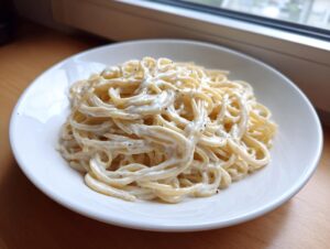 A white plate piled high with creamy spaghetti tossed in a rich sauce, representing amazing 20-minute parmesan pasta.