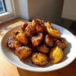 A white bowl piled high with golden brown, crispy roasted potatoes seasoned with rosemary and coarse salt.