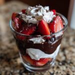 Close-up of a layered dubai chocolate strawberry cup with whipped cream and chocolate shavings.