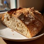 A close-up of a freshly baked dutch oven no knead crusty bread, showing the open, airy crumb structure.