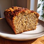 A close-up of a freshly baked loaf slice of easy oatmeal banana bread showing a moist, textured crumb.