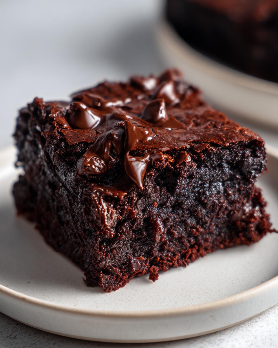 Close-up of a rich, fudgy zucchini brownies square topped with melted chocolate chips.
