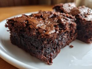 Close-up of a rich, fudgy zucchini brownies square showing a shiny, cracked top and moist interior.