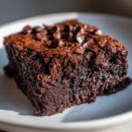 Close-up of a fudgy, rich square of zucchini brownies topped with melted chocolate chips.