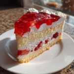 Close-up of a delicious slice of german strawberry cake with layers of sponge, cream, and bright red strawberry jelly topping.