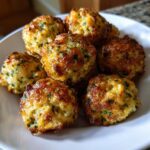 Close-up of several golden brown, crispy stuffing balls seasoned with parsley, served on a white plate.
