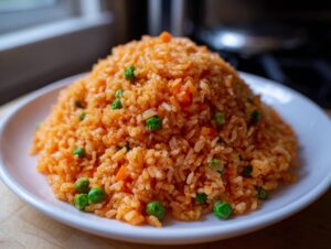 A perfectly mounded serving of vibrant orange homemade mexican rice mixed with bright green peas on a white plate.