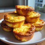 A stack of golden brown, fluffy homemade starbucks egg bites piled high on a white plate.