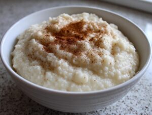 Close-up of creamy Jamaican cornmeal porridge with coconut milk, topped with a dusting of cinnamon.