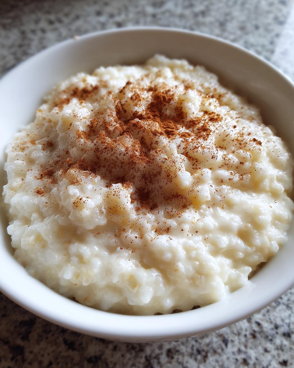 Close-up of creamy Jamaican cornmeal porridge with coconut milk, topped generously with ground cinnamon.