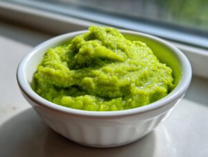 A close-up of vibrant green lemon parmesan edamame purée mounded high in a small white bowl.