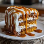 Close-up of a delicious slice of pumpkin cake with cream cheese frosting and salted caramel drizzle.