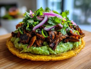 Close-up of a single roasted mushroom tostada topped with creamy avocado mash and fresh cilantro and red onion.