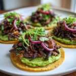Four roasted mushroom tostadas topped with bright green guacamole, pickled red onions, and fresh cilantro.