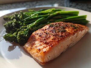 A close-up of a perfectly seared fillet of salmon next to bright green broccolini, ready for a salmon broccolini dinner.
