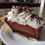 A perfect slice of french silk pie featuring two layers of chocolate filling, topped with whipped cream and chocolate shavings.