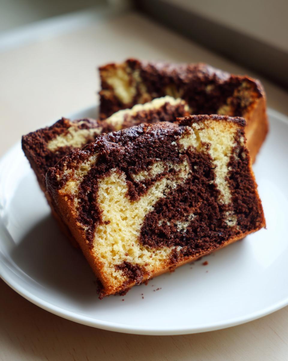 Close-up of three moist slices of german marble cake showing the distinct vanilla and chocolate swirl pattern.