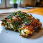 Close-up of a perfectly cooked piece of Baked Chicken Thighs with Spring Herbs, featuring crispy skin and fresh green herbs.
