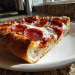 Close-up of a thick slice of Deep Dish Pepperoni Pizza showing the high, golden crust, melted cheese, and crispy pepperoni.