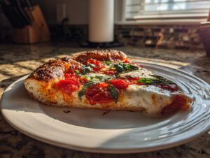 A close-up of a slice of Homemade Margherita Pizza featuring melted mozzarella, bright tomatoes, and fresh basil.