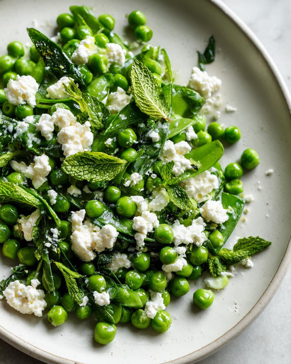 Close-up of a vibrant Spring Pea and Feta Salad with fresh mint leaves on a light plate.