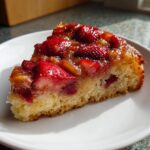 A close-up slice of moist Strawberry Rhubarb Upside Down Cake with a glossy, caramelized fruit topping.